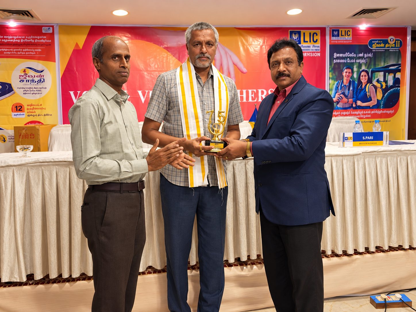 G. Selvakumar receiving a commemorative trophy on stage at an LIC meet